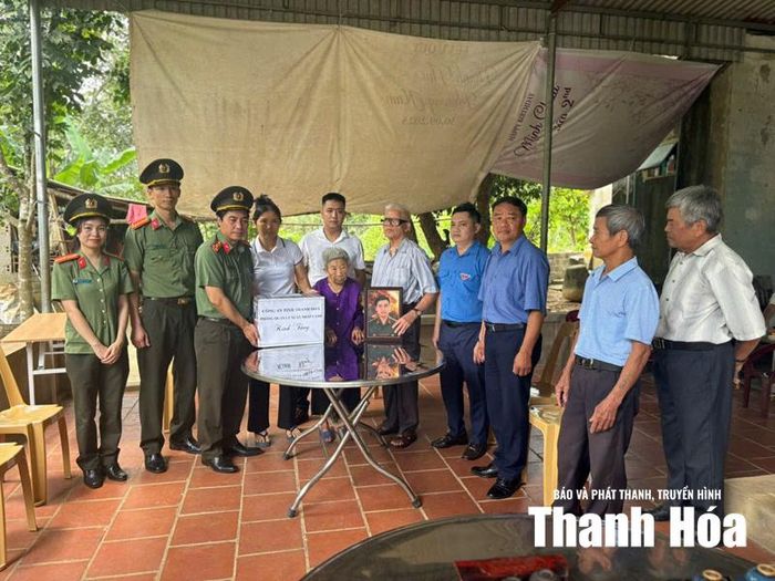 Cán bộ, chiến sĩ Phòng Quản lý xuất nhập cảnh, Công an tỉnh Thanh Hóa trao quà và ảnh liệt sĩ được phục dựng cho gia đình chính sách tại xã Sao Vàng.