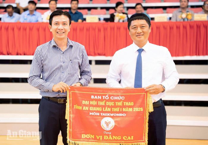 Phó Giám đốc Sở Văn hóa và Thể thao Trần Nguyễn Bá trao cờ đăng cai cho lãnh đạo UBND phường Châu Đốc.