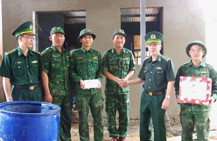 Đại tá Phan Thăng Long tặng quà động viên cán bộ, chiến sĩ đang hỗ trợ xây nhà cho gia đình ông Mấu Hoành.