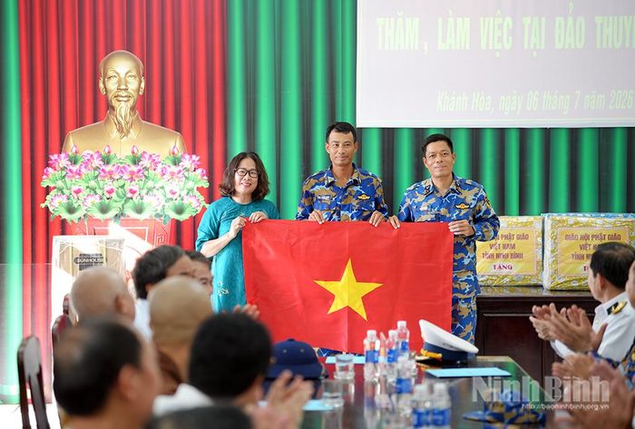 Đồng chí Phạm Kim Huệ, Phó Giám đốc Báo và phát thanh, truyền hình Ninh Bình trao tặng cờ cho đại diện đảo Thuyền Chài.