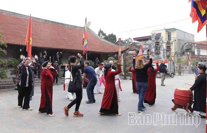 Các thành viên cao tuổi cùng lớp kế cận của phường Xoan An Thái hướng dẫn du khách nước ngoài trải nghiệm hát Xoan tại Đình Hùng Lô.