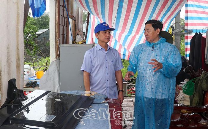 Đồng chí Nguyễn Quốc Tiến, Bí thư Đảng ủy, Chủ tịch HĐND xã Khánh Bình (bên phải), báo cáo nhanh tình hình thiên tai và biện pháp khắc phục của địa phương với đồng chí Hồ Thanh Thủy, Chủ tịch Ủy ban MTTQ Việt Nam tỉnh Cà Mau.