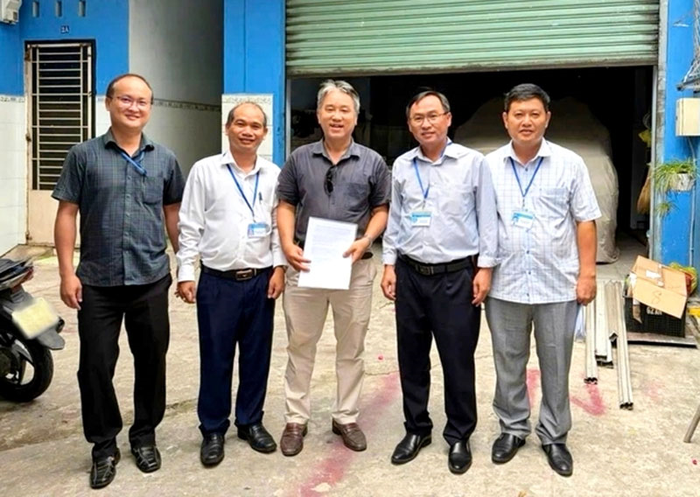 Đại diện Phòng Kinh tế và Trung tâm Phục vụ hành chính công xã Bà Điểm trao thông báo sửa chữa nhà ở đến một trường hợp ảnh hưởng bởi dự án cải tạo, nâng cấp quốc lộ 22 (nay là đường Lê Quang Đạo). Ảnh: Phòng Kinh tế xã Bà Điểm cung cấp