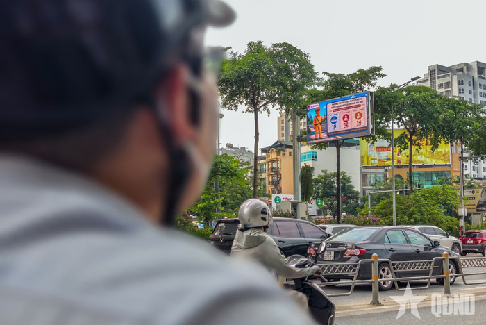 Người dân theo dõi màn hình LED hoặc phương tiện lưu thông qua khu vực.