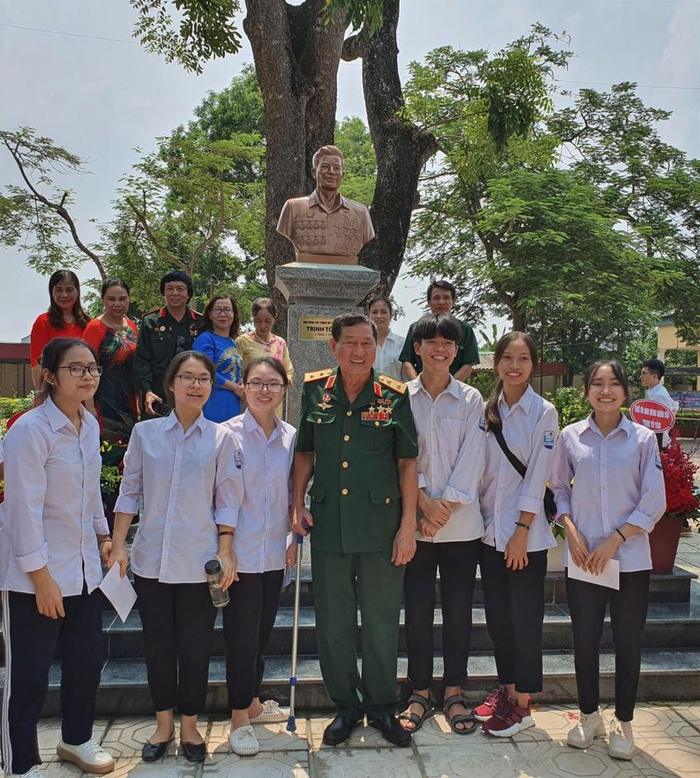 Các đại biểu chụp ảnh lưu niệm bên bức tượng Anh hùng LLVT nhân dân Trịnh Tố Tâm tại Trường THPT Ứng Hòa B trong ngày khánh thành. Ảnh: BÍCH TRANG