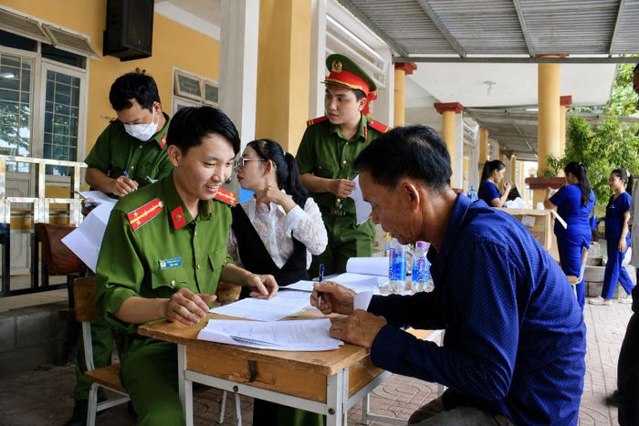 Công an xã Vạn Tường hỗ trợ thân nhân gia đình liệt sĩ làm thủ tục. Ảnh: NGUYỄN TRANG