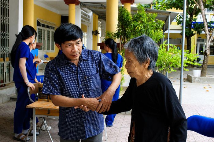 Người con trai đưa mẹ già đi tìm các anh, các chị đã hy sinh. Ảnh: NGUYỄN TRANG