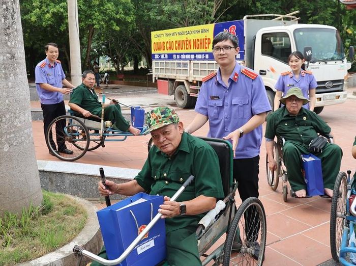 Các thành viên đoàn công tác VKSND tối cao hỗ trợ các bác thương binh, bệnh binh từ hội trường Trung tâm về phòng nghỉ.