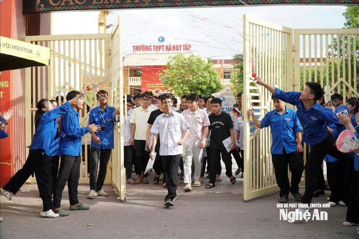 Những thí sinh đầu tiên bước ra khỏi điểm thi Trường THPT Hà Huy Tập trong sự cổ vũ của các học sinh tình nguyện. Ảnh: Mỹ Hà