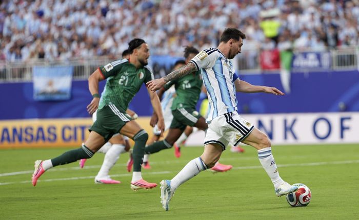 Tiền đạo Argentina Lionel Messi (phải) đi bóng qua các tuyển thủ Algeria. Ảnh: THX/TTXVN