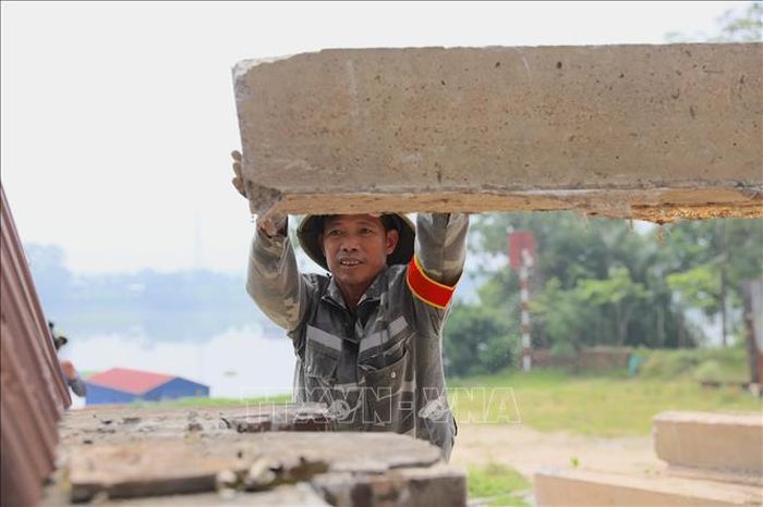 Thành viên lực lượng xung kích giữ ổn định tấm phai trong quá trình thực hành đóng cửa khẩu đê. Ảnh: Trung Nguyên/TTXVN