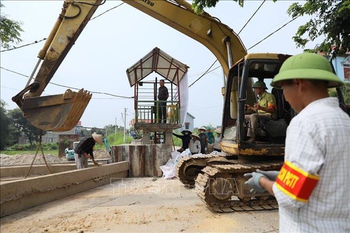 Tấm phai bê tông được phương tiện cơ giới nâng khỏi vị trí tập kết để đưa tới khe cửa khẩu đê Đô Tân. Ảnh: Trung Nguyên/TTXVN