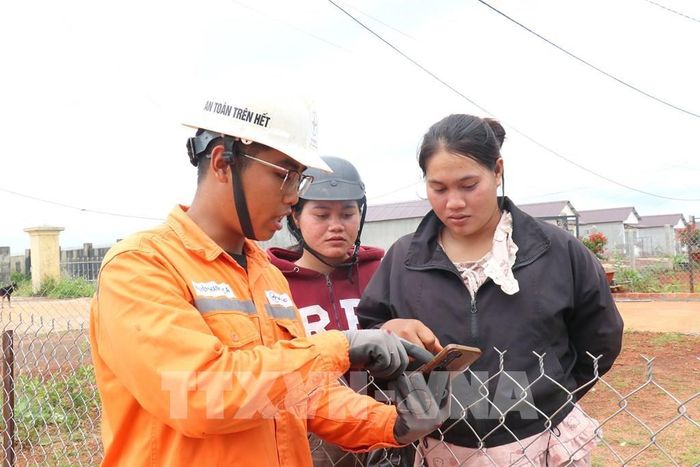 Nhân viên quản lý vận hành đường dây thuộc Điện lực Tuy Đức (Công ty Điện lực Lâm Đồng) hướng dẫn người dân sử dụng app thông qua điện thoai thông minh tại điểm dân cư liền kề bon Bu Dăr, xã biên giới Quảng Trực, (tỉnh Lâm Đồng). Ảnh Thanh Vũ - TTXVN