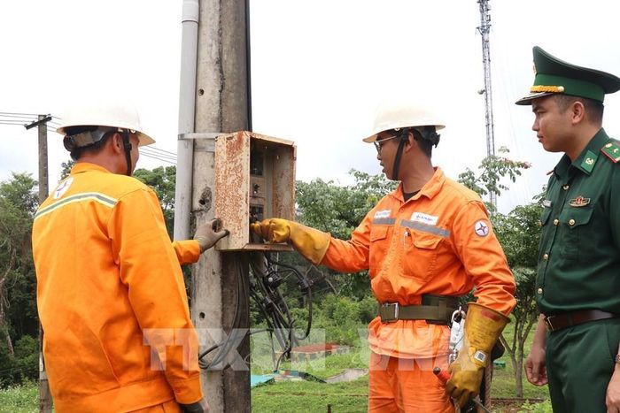 Thiếu tá Nguyễn Văn Chinh, Phó Đồn trưởng Đồn Biên phòng Cửa khẩu Bu Prăng, xã Quảng Trực (tỉnh Lâm Đồng), cùng nhân viên Điện lực Tuy Đức kiểm tra hệ thống điện vùng biên. Ảnh Thanh Vũ - TTXVN