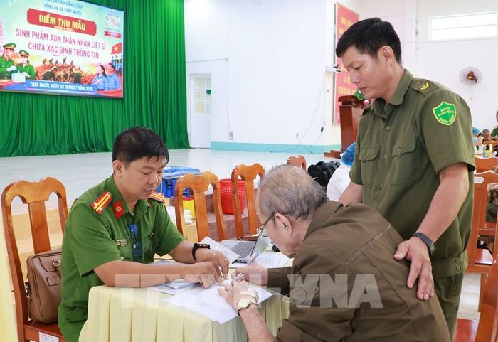 Thân nhân liệt sĩ được lực lượng công an hỗ trợ thủ tục để lấy mẫu sinh phẩm ADN. Ảnh: Nhựt An - TTXVN