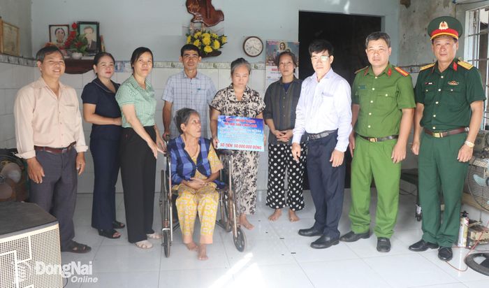 Lãnh đạo phường Dầu Giây và các ngành, đoàn thể trao bảng tượng trưng 50 triệu đồng hỗ trợ sửa chữa nhà cho bà Nguyễn Thị Hải Yến. Ảnh: Nhật Quang