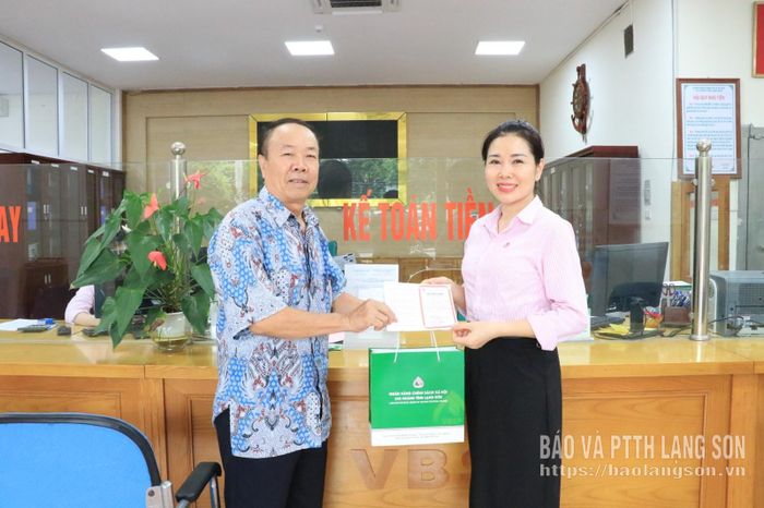 Cán bộ Chi nhánh Ngân hàng Chính sách xã hội tỉnh trao sổ tiết kiệm cho đại biểu tham gia gửi tiết kiệm tại ngày hội