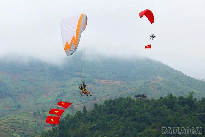 Giữa không gian hùng vĩ của đèo Khau Phạ, tỉnh Lào Cai, lá cờ Tổ quốc đỏ thắm nổi bật giữa bầu trời, tạo điểm nhấn đầy tự hào và cảm xúc. Bức ảnh ghi lại khoảnh khắc hòa quyện giữa thể thao mạo hiểm dù lượn và vẻ đẹp thiên nhiên vùng cao, mang đến cảm giác tự do, phóng khoáng. Đây không chỉ là hoạt động thu hút du khách mà còn góp phần quảng bá hình ảnh Khau Phạ – một trong những điểm bay dù lượn đẹp hàng đầu Việt Nam.
