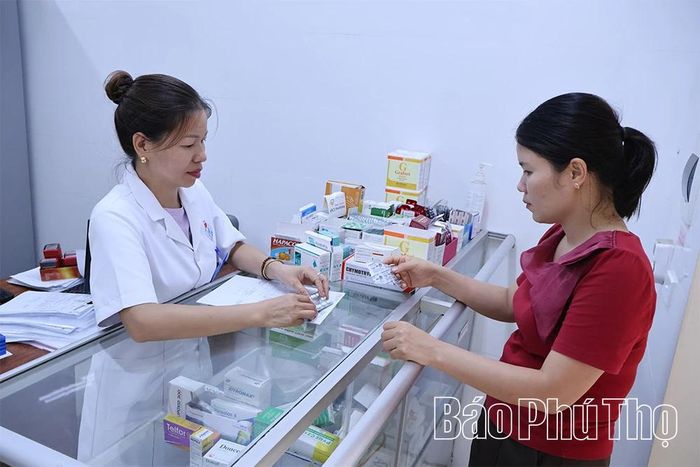 Cán bộ Trạm Y tế xã cấp thuốc bảo hiểm y tế cho người bệnh.