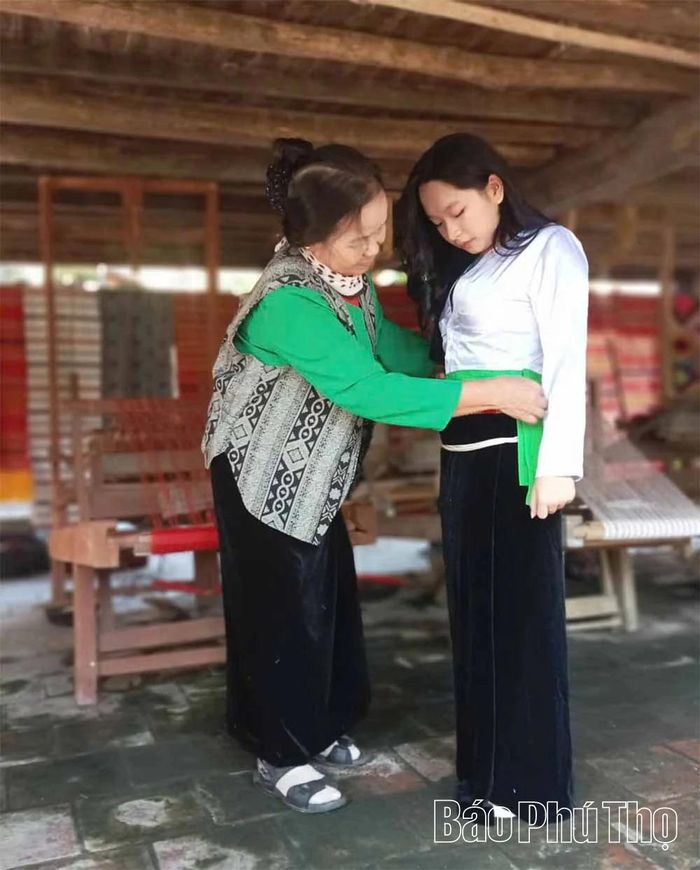 Bà Sa Thị Tâm hướng dẫn du khách trải nghiệm trang phục truyền thống người Mường.