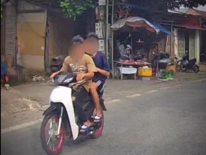 Hình ảnh hai thanh thiếu niên không đội mũ bảo hiểm, xe không biển số, di chuyển với tốc độ cao trên đường.