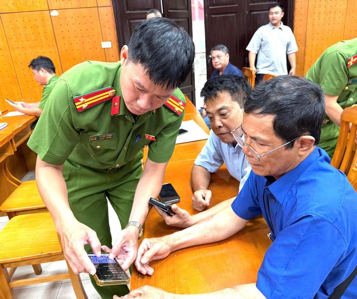 Lực lượng Công an phường hướng dẫn các đại biểu cài đặt và sử dụng ứng dụng "Báo cháy 114". Ảnh: PV