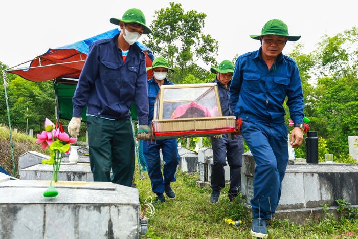 Các tiểu quách sau khi được đưa ra khỏi phần mộ được phủ Quốc kỳ và cẩn trọng di chuyển đến khu vực lấy mẫu sinh phẩm.