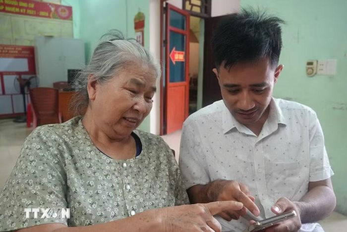 Cán bộ thôn Ngư Lộc (Thanh Hóa) hỗ trợ người dân cập nhật công nghệ thông tin, chuyển đổi số. (Ảnh: Khiếu Tư/TTXVN)