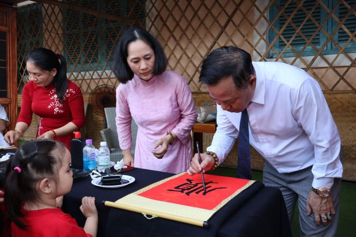 Khách thăm quan hào hứng tham gia trải nghiệm mài mực, tập cầm bút lông viết chữ Hán, in tranh mộc bản...