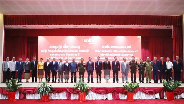 Đại biểu hai nước chụp ảnh kỷ niệm nhân buổi chiếu bộ phim điện ảnh đặc biệt “Mưa đỏ” tại Lào. Ảnh: Xuân Tú/PV TTXVN tại Lào