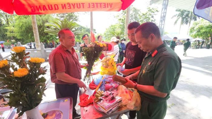 Thương binh, CCB Trần Côn Sơn (phải) cùng con trai sắp lễ tại Nghĩa trang liệt sĩ Vị Xuyên. Ảnh: Thu Thủy.