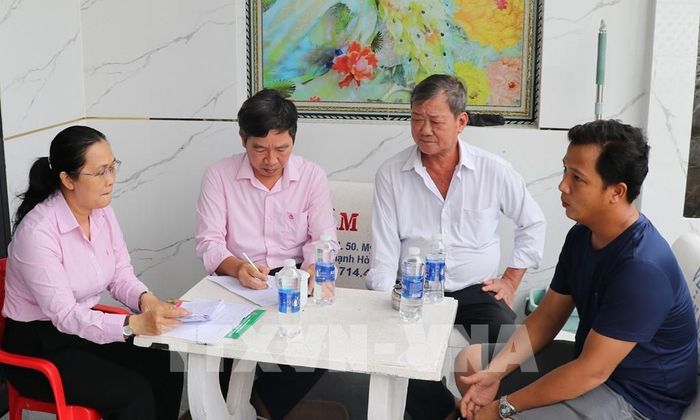 Bà Trần Thị Hoàng Quyên (trái), Giám đốc Phòng Giao dịch Ngân hàng Chính sách xã hội Châu Thành, trao đổi với hộ nhận nguồn vốn tín dụng. Ảnh: Hữu Chí - TTXVN