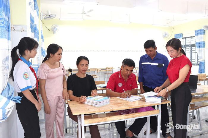 Phụ huynh, học sinh và giáo viên Trường THCS Tiến Thành làm thủ tục mượn sách từ Thư viện sách giáo khoa dùng chung.