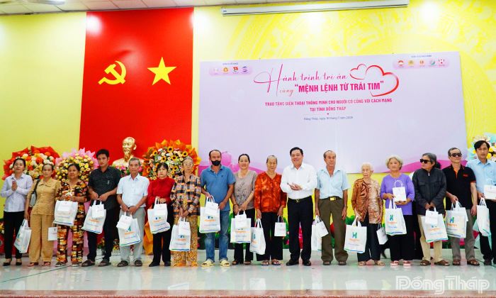 Đại biểu tham dự và các đơn vị trao tặng điện thoại thông minh cho người có công với cách mạng.