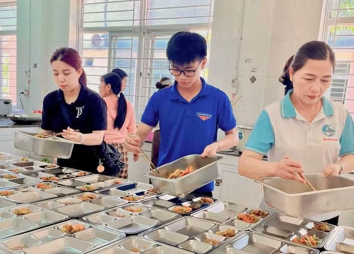  Nguyên (giữa) là người trẻ nhất trong số những tình nguyện viên tham gia các buổi nấu cơm 0 đồng. Ảnh: NVCC 