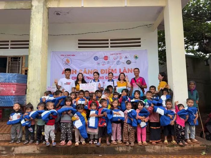  Anh Hồ Ngọc Sơn (áo trắng, bìa trái) cùng nhà tài trợ trao quà cho các em nhỏ của điểm trường khó khăn. Ảnh: H.H 