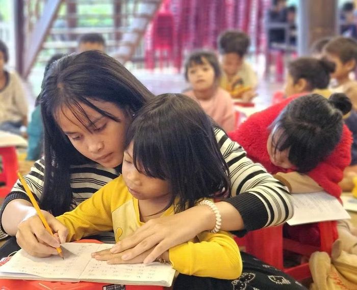  Các em chuẩn bị vào lớp 1 được giáo viên tình nguyện hướng dẫn làm quen với tiếng Việt. Ảnh: Ngọc Duy 