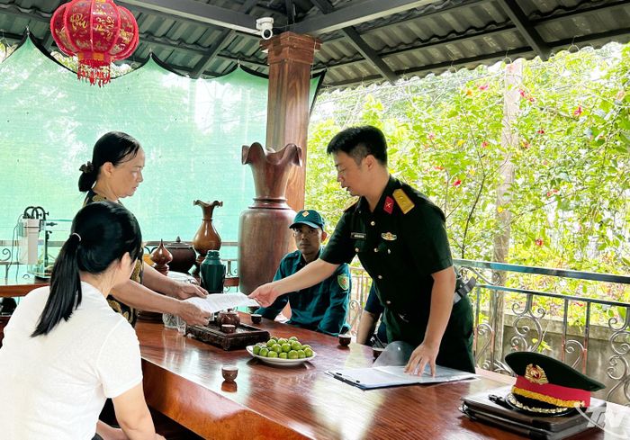Trung tá Nguyễn Xuân Giang (bên phải), Chính trị viên phó, Ban CHQS xã Tân Cương, cung cấp mẫu thông tin cho gia đình bà Đào Thị Hưởng, xóm Nam Hưng.