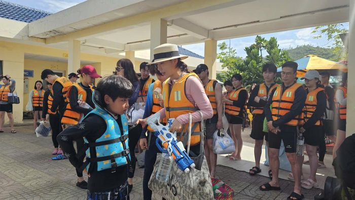 Du khách nước ngoài mặc áo phao trước khi xuống tàu ra đảo.