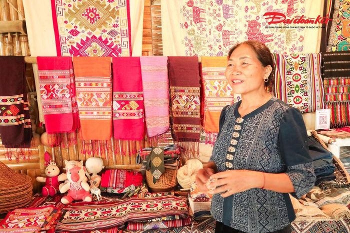 Nghệ nhân Sầm Thị Bích ở bản Hoa Tiến, xã Châu Tiến (Nghệ An) bên gian hàng thổ cẩm do chính tay bà làm ra. Ảnh: ĐB