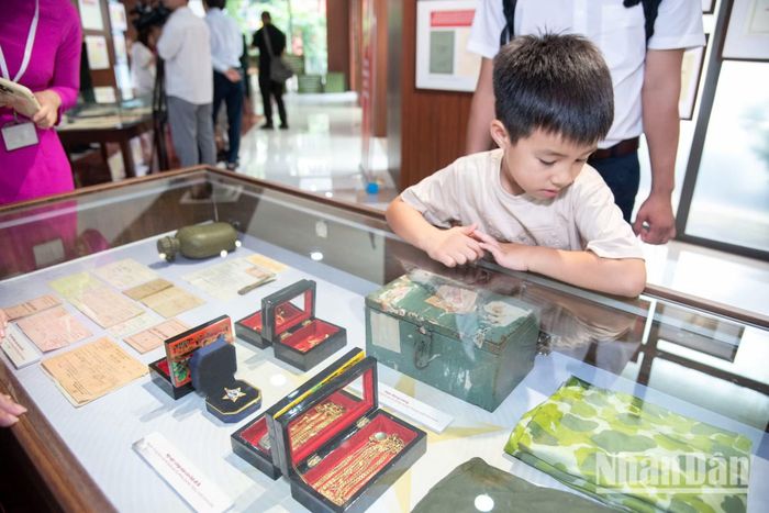 Cậu bé 6 tuổi chăm chú nhìn những kỷ vật nhỏ bé của cha ông. Những bài học về lòng yêu nước bắt đầu từ những trải nghiệm thực tế thế này.