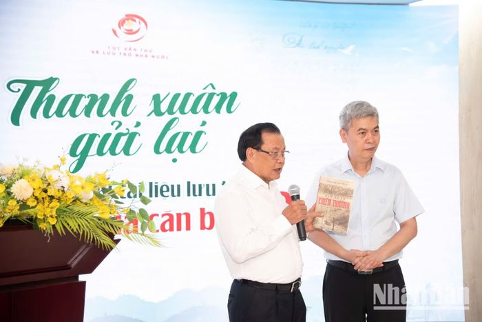 Ông Phạm Quang Nghị, nguyên Ủy viên Bộ Chính trị, nguyên Bí thư Thành ủy Hà Nội, một cán bộ đi B, trao sách tác phẩm “Nơi ấy là chiến trường” cho ông Đặng Thanh Tùng, Cục trưởng Cục Văn thư và Lưu trữ Nhà nước.