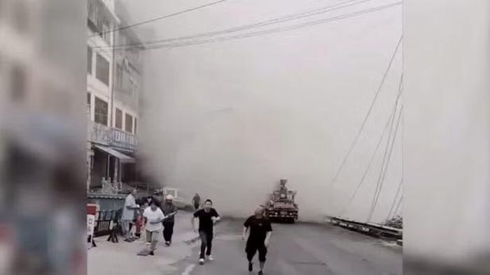 Cột bụi dày đặc bốc lên phía sau những người dân đang vội vàng tháo chạy khi vụ sạt lở xảy ra. Ảnh: X.