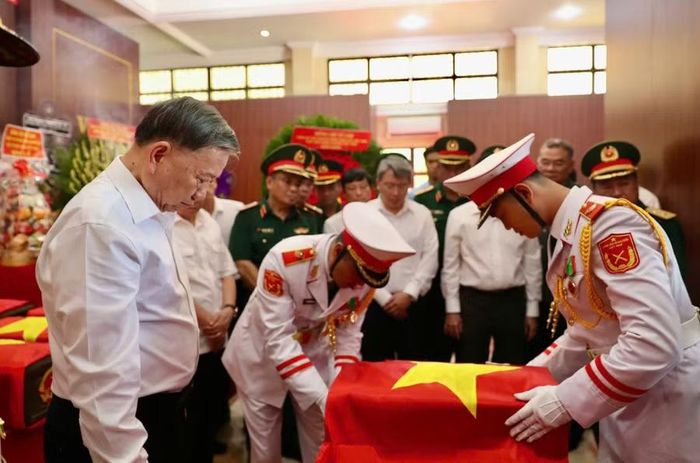 Tổng Bí thư, Chủ tịch nước Tô Lâm thực hiện nghi lễ phủ Quốc kỳ linh thiêng lên quách chứa hài cốt các Anh hùng liệt sĩ vừa được tìm thấy tại công viên Lê Thị Riêng. (Ảnh: BTC)