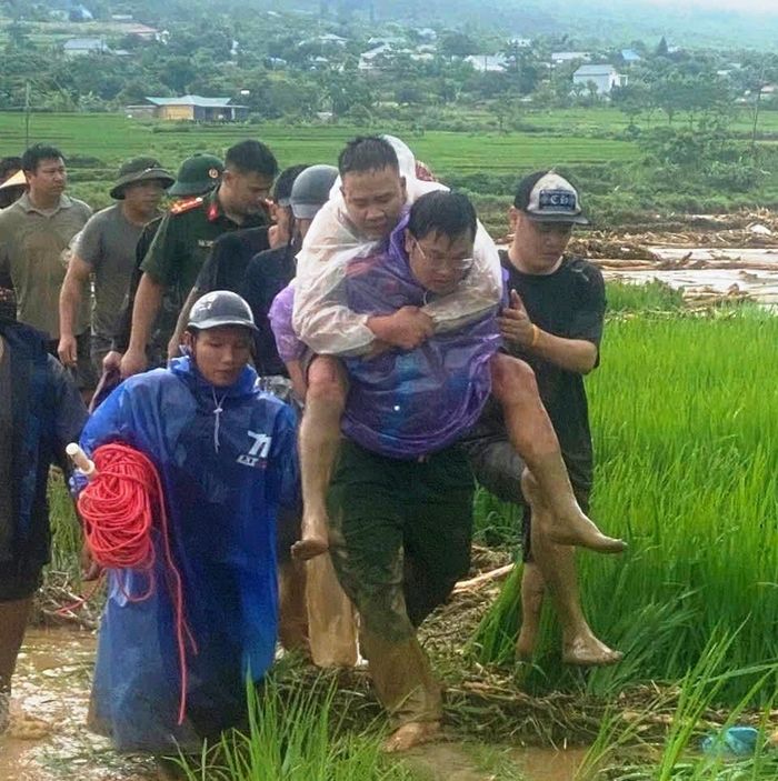 Công an cùng chính quyền địa phương giải cứu 2 người dân mắc kẹt giữa dòng nước lũ. Ảnh: M.T