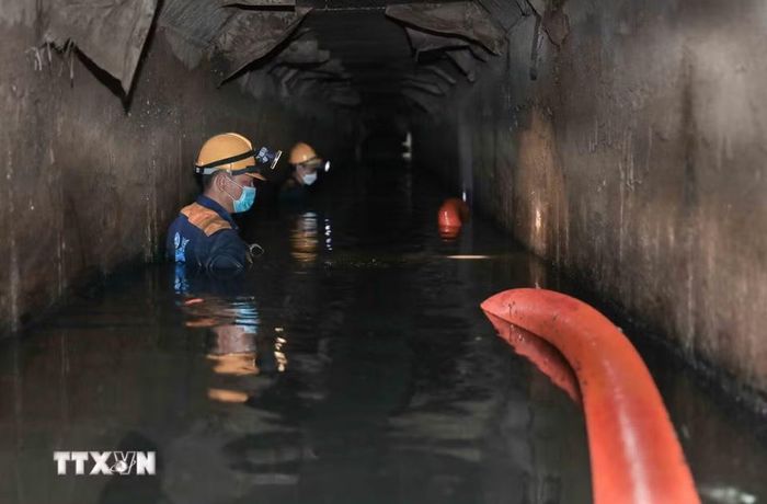 Ngâm mình dưới dòng nước đen ngòm để hút sạch bùn thải, khơi thông dòng chảy cho Thủ đô. (Ảnh: Phan Phương/TTXVN)