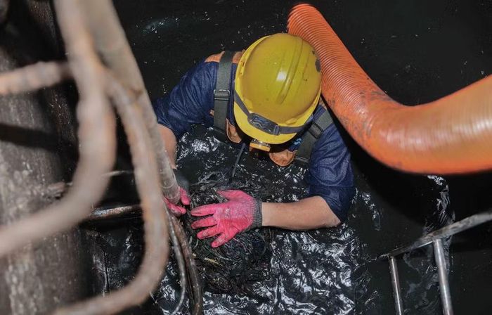 Trực tiếp ngâm mình dưới dòng nước cống đen ngòm để khơi thông dòng chảy, đảm bảo cuộc sống bình yên cho người dân Thủ đô. (Ảnh: Phan Phương/TTXVN)