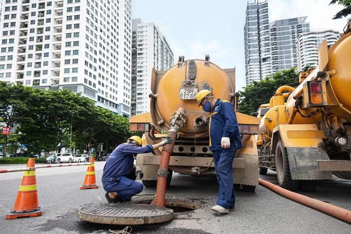 Công nhân trực tiếp xuống cống ngầm thu gom rác để vận chuyển về khu tập kết xử lý. (Ảnh: Tiến Long/TTXVN phát)