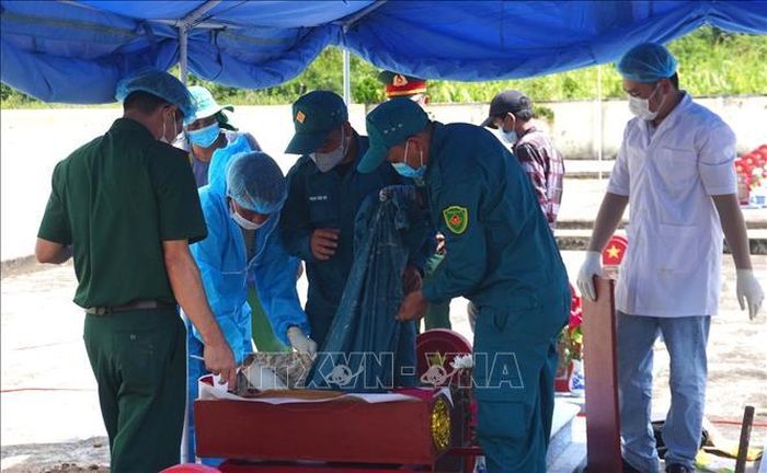 Các chiến sĩ, bác sĩ pháp y lấy mẫu sinh phẩm tại các mộ liệt sĩ để mang đi xét nghiệm ADN. Ảnh: Tường Quân/TTXVN