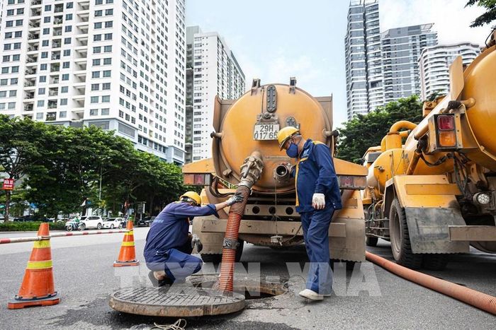 Công nhân trực tiếp xuống cống ngầm thu gom rác để vận chuyển về khu tập kết xử lý. Ảnh: Tiến Long/TTXVN phát